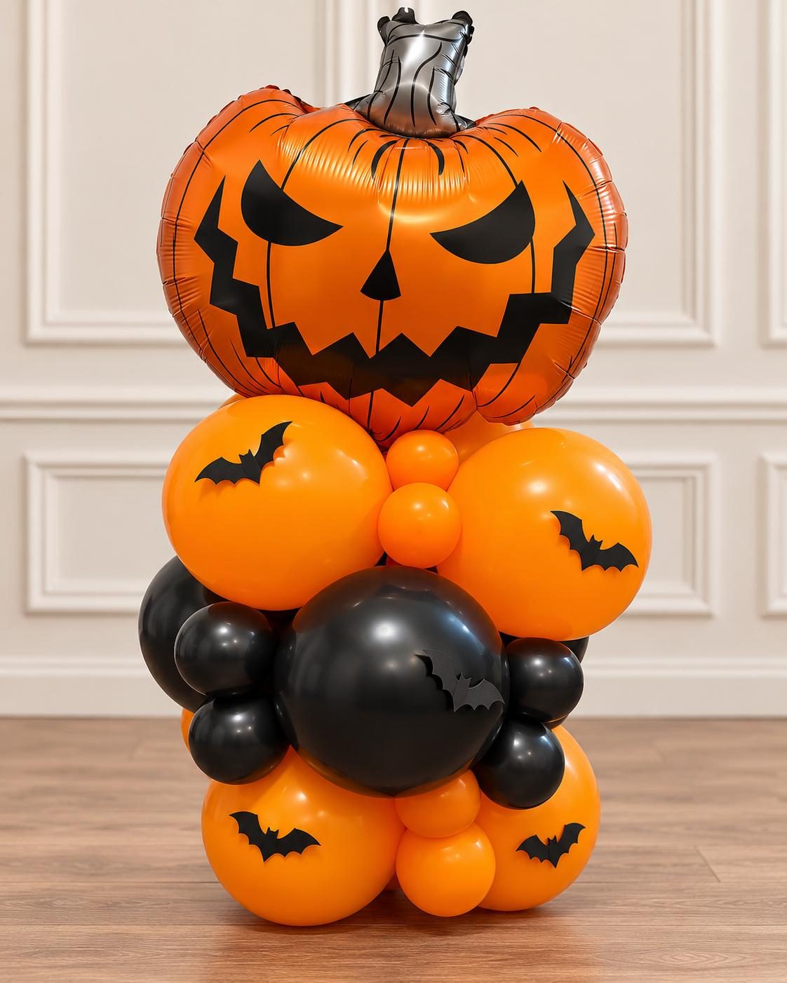 Estructura de globos pequeña en naranja y negro con una calabaza en la punta y calcomanías de murciélagos