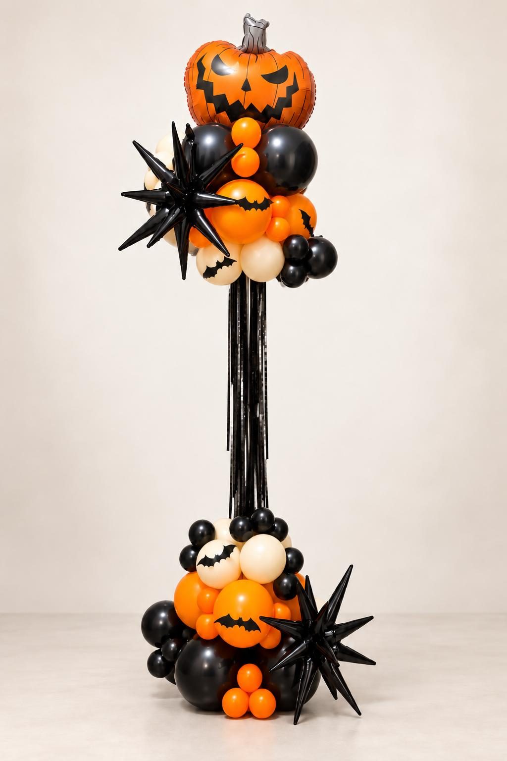 Estructura de globos alta y ajustable para Halloween con estrellas negras, flecos y una calabaza en la punta