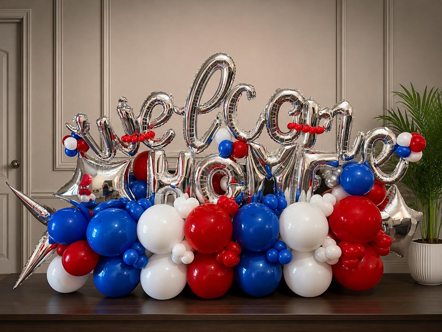 Letras plateadas de welcome home sobre una guirnalda de globos rojos, blancos y azules con estrellas plateadas